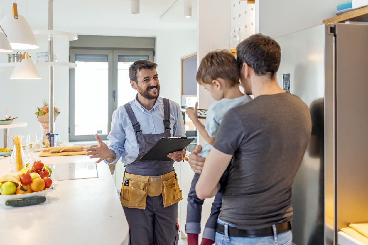 A father discussing kitchen renovations with a construction firm worker while holding his son.